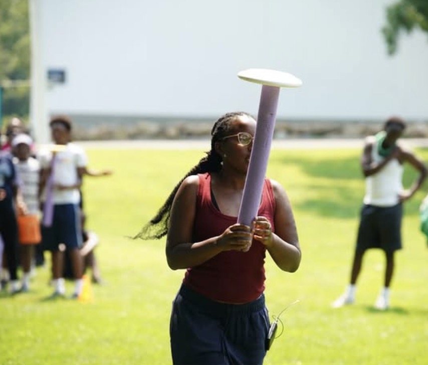 A camper balancing a team-building game piece in the field