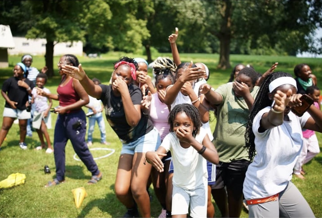 Campers dancing and cheering on the lawn at Camp Mahoro