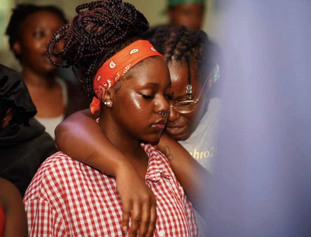 A camper being comforted and prayed over by a friend